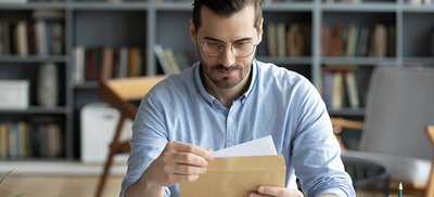 Mann öffnet Schreiben mit Steuer-ID